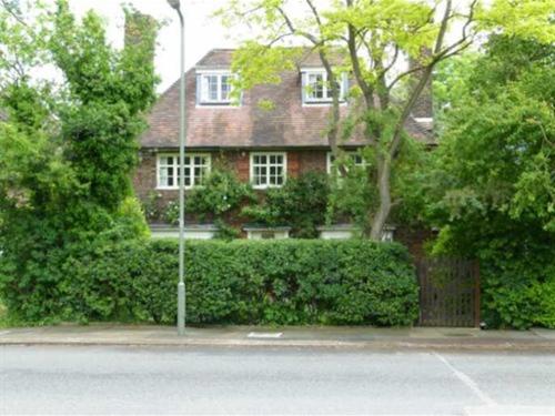 une maison en briques rouges avec des buissons et une rue dans l'établissement Iolanthe, à Londres
