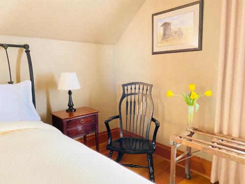 a bedroom with a bed and a chair and a vase of flowers at Princess and the Pea Hotel in Langley
