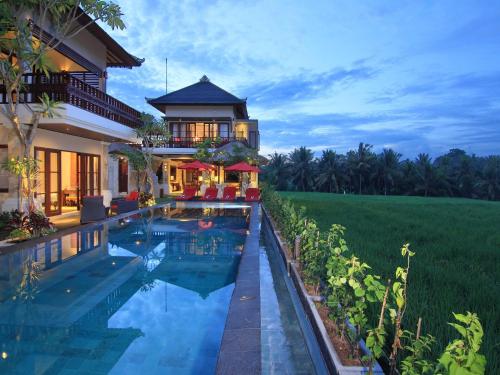 a villa with a swimming pool in front of a house at Uma Stana Villa in Ubud