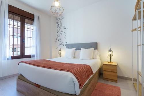 a white bedroom with a large bed and windows at Apartamentos Baiti Ronda in Ronda