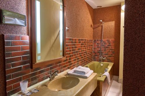uma casa de banho com um lavatório e uma parede de tijolos em Aux Prisons de Montagny em Montagny