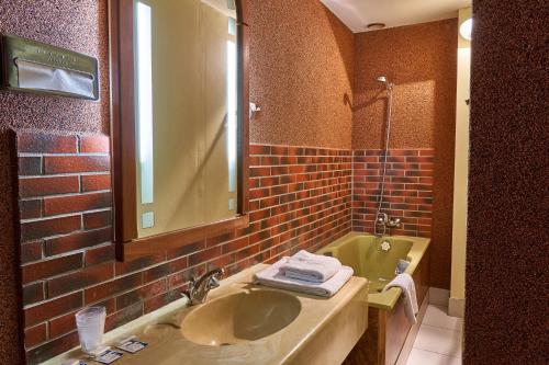 a bathroom with a sink and a brick wall at Aux Prisons de Montagny in Montagny