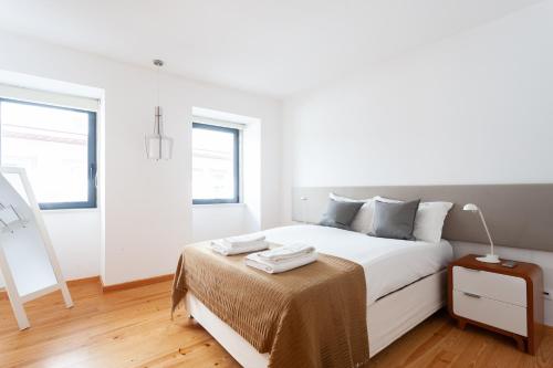 a white bedroom with a bed and a table at FLH Liberdade Contemporary Flat in Lisbon