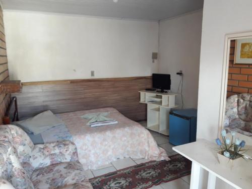 a bedroom with a bed and a chair and a television at Hotel Pousada Casa Nostra in Erechim