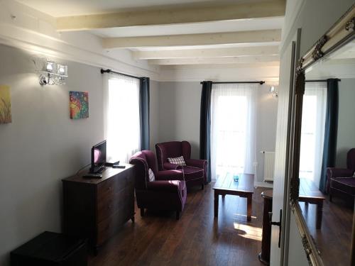 a living room with two chairs and a desk and two windows at Varga Villa in Orfű