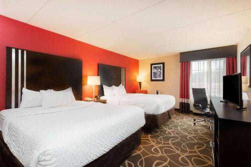 a hotel room with two beds and a flat screen tv at La Quinta Inn & Suites - New River Gorge National Park in Summersville