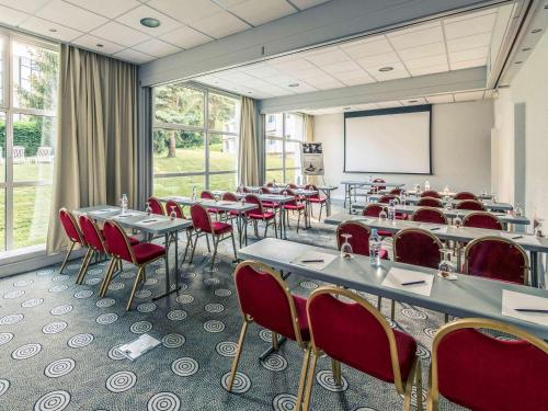 a conference room with tables and chairs and a screen at Mercure Annecy Sud in Annecy