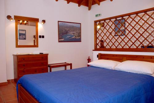 a bedroom with a blue bed and a wooden dresser at Vila Elena 1astoning view in Steni Vala Alonissos