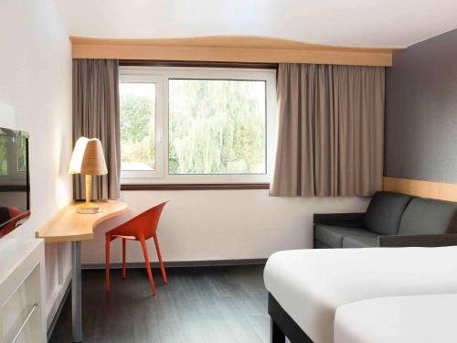 una stanza d'albergo con un letto, una sedia e una finestra di ibis 3 Lacs Neuchâtel a Thielle