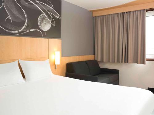 una stanza d'albergo con un letto e una sedia di ibis 3 Lacs Neuchâtel a Thielle