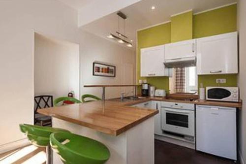 a kitchen with white and green cabinets and green chairs at Barla 3 - a spacious one bedroom apartment near Place Garibaldi in Nice