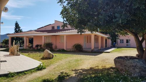 a pink house with a tree in front of it at Agriturismo Sa Mandria in Castiadas