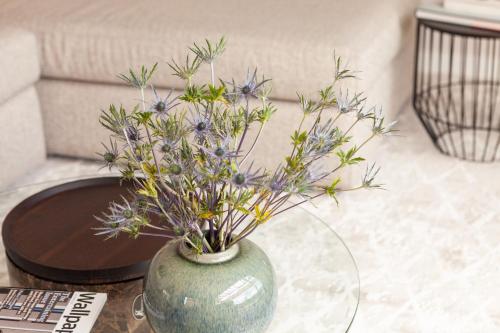 a green vase with purple flowers on a table at Cassa Luxury Homes in Bogotá