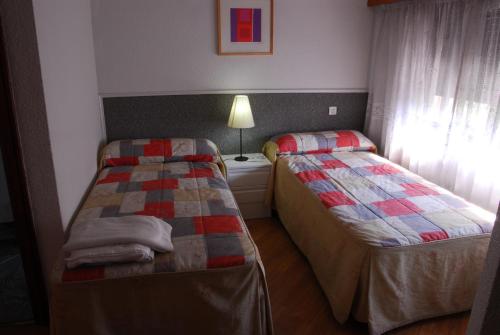 Duas camas num pequeno quarto com uma janela em Apartamentos Goya 75 em Madri