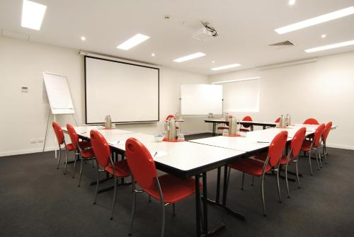 a room filled with tables, chairs, and a projector screen at Adara Richmond in Melbourne
