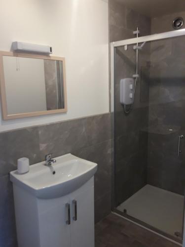 a bathroom with a sink and a shower with a mirror at The Anchorage in Saint Margarets Hope