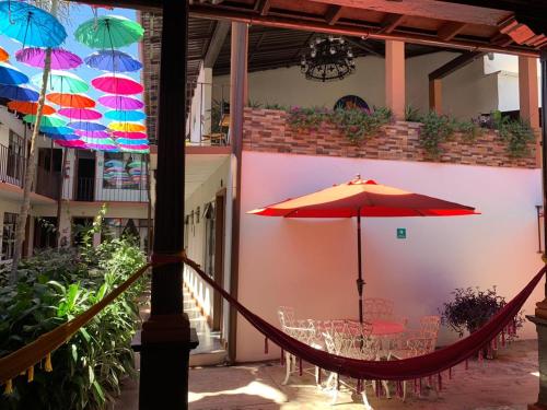 a patio with a hammock and a table with an umbrella at Hotel Villa de Flores in Uruapan del Progreso