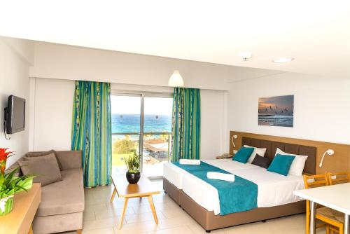 a bedroom with a bed and a living room at Helios Bay Hotel and Suites in Paphos
