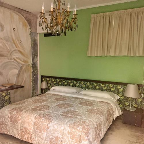 a green bedroom with a bed and a chandelier at Locanda Cortiletto d'Alba in Alba