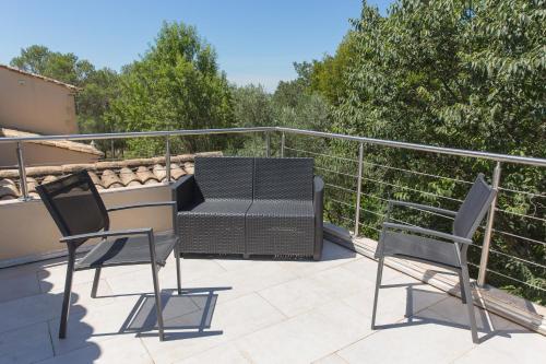 a patio with two chairs and a grill on a balcony at Le Mas des Alexandrins in Uzès