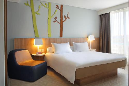 a bedroom with a large bed and a chair at Grand Livio Kuta Hotel in Legian