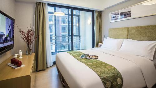 a bedroom with a large bed and a large window at Citadines Zhuankou Wuhan in Wuhan