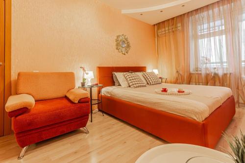 ニジニ・ノヴゴロドにあるУютная квартира с качелями на верандеのベッドルーム(オレンジ色のベッド1台、椅子付)