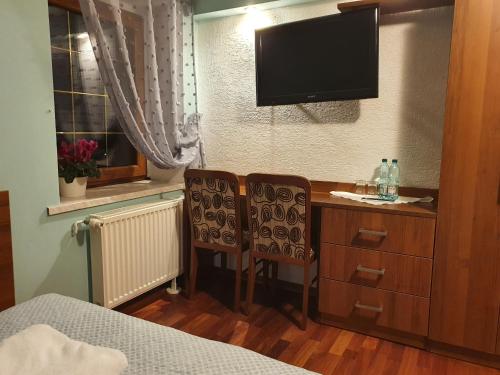 a bedroom with a desk with two chairs and a television at Chata nad Sztolnią in Bystrzyca Górna