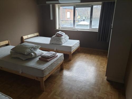 two beds in a room with a window at Residentie 't Leugentje in Grembergen