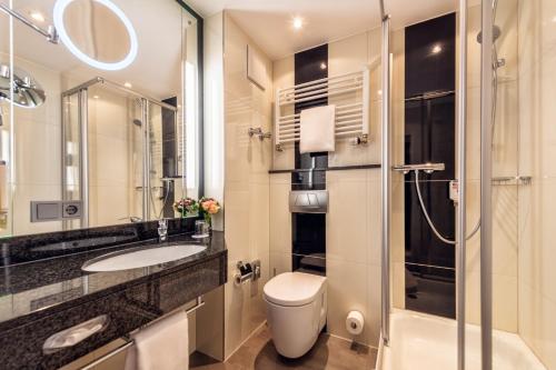 a bathroom with a toilet and a sink and a shower at Best Western Plus Hotel Stadtquartier Haan in Haan