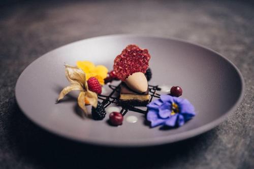 a dessert on a white plate with berries and flowers at Der Löwe in Burgberg