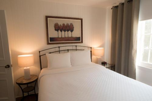 a bedroom with a large white bed with two lamps at Hôtel Le Rivage in Rosemère