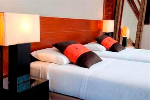 two beds with red pillows in a bedroom at Oure Lodge Beach Resort in Vao