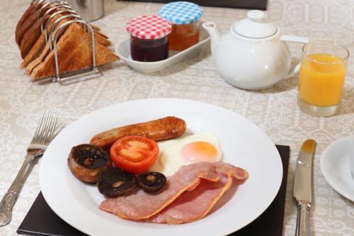 een bord ontbijtproducten met eieren, worst en tomaten bij Inglestone House Guest House in Kelso