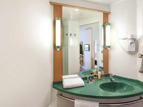 een badkamer met een groene wastafel en een spiegel bij Ibis Budget Valencia Aeropuerto in Manises