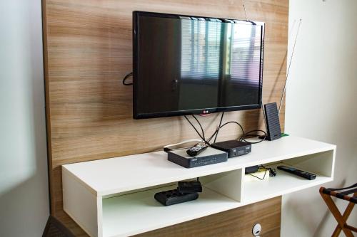 a flat screen tv on a white shelf at Kit Net - Vila Verde Sudoeste in Brasilia