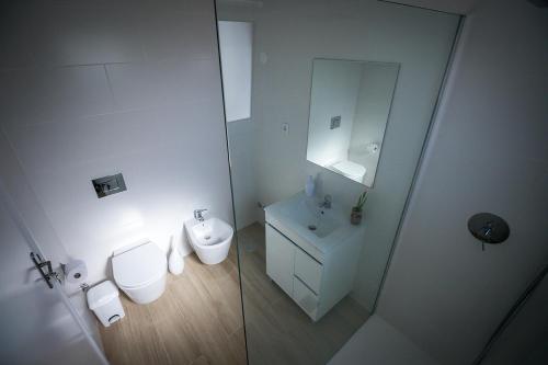 a white bathroom with a toilet and a sink at Ponta Delgada Guest House 2 in Arrifes