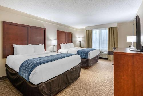 a hotel room with two beds and a television at Comfort Inn & Suites in Heath
