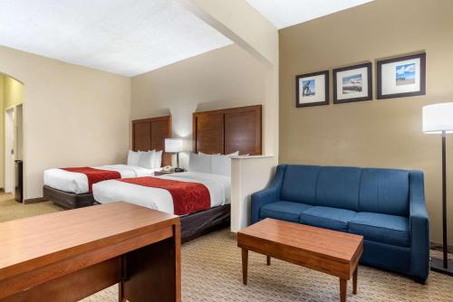 a hotel room with two beds and a blue couch at Comfort Suites Airport in Jacksonville