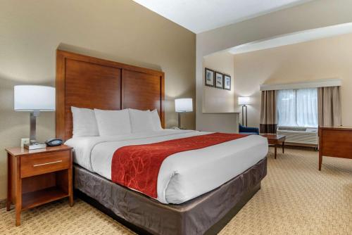 a hotel room with a large bed with a red blanket at Comfort Suites Airport in Jacksonville