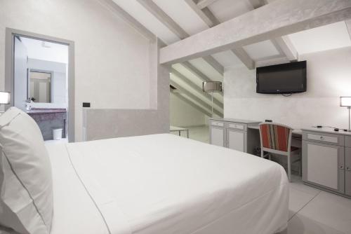 a white bedroom with a bed and a tv at Best Western Modena District in Campogalliano