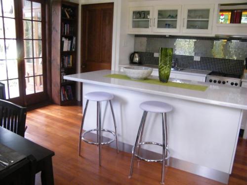 a kitchen with two bar stools and a counter at Mount Browne Cottage in Coffs Harbour