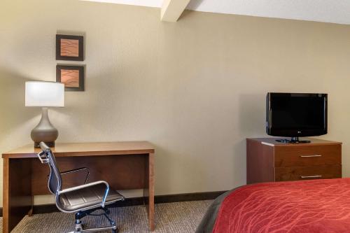 a room with a bed and a desk with a television at Comfort Inn & Suites Suwanee - Sugarloaf in Suwanee