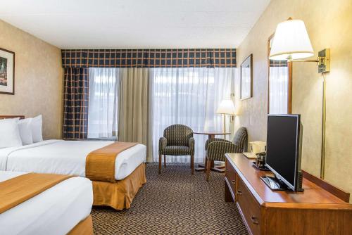 a hotel room with two beds and a desk with a television at Quality Inn and Conference Center in Springfield