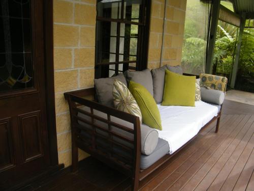 a couch with colorful pillows sitting on a porch at Mount Browne Cottage in Coffs Harbour
