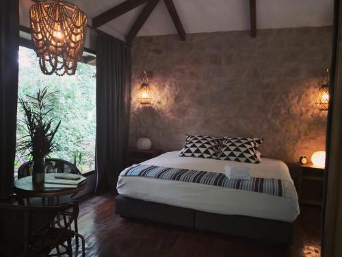 1 dormitorio con cama, mesa y ventana en Boutique Hotel y Spa Tangara Azul, en Ojochal