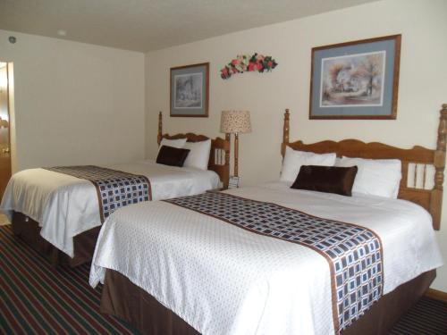 Una habitación de hotel con dos camas con sábanas blancas. en Der Ruhe Blatz Motel, en Shipshewana