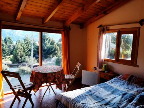 1 dormitorio con mesa, cama y ventana en EL TUKI en Villa Traful