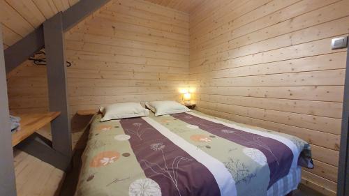 een slaapkamer met een bed in een houten hut bij Le Frenola in Saint-Pierre-dʼEntremont