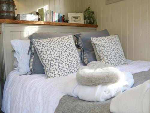 a bed with blue and white pillows and a white blanket at Gibson's Hut in Preston Candover